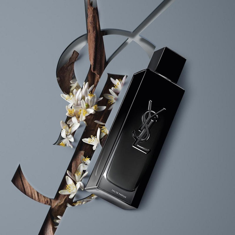 Black YSL perfume bottle with flowers on a gray background