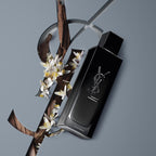 Black YSL perfume bottle with flowers on a gray background