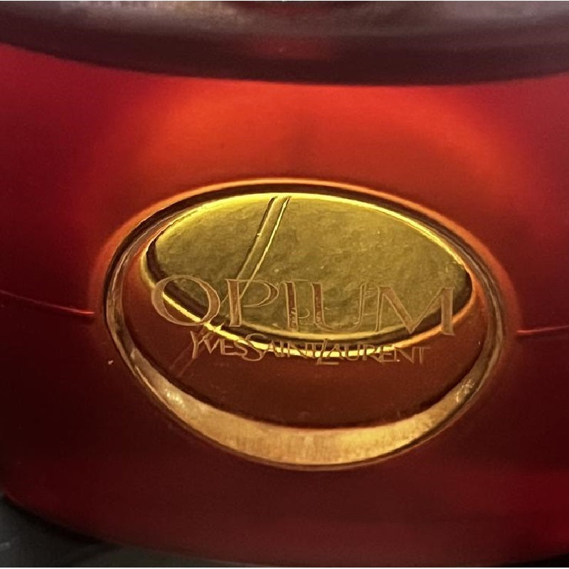 Close-up of a red product with a gold 'Opium' logo on a dark background