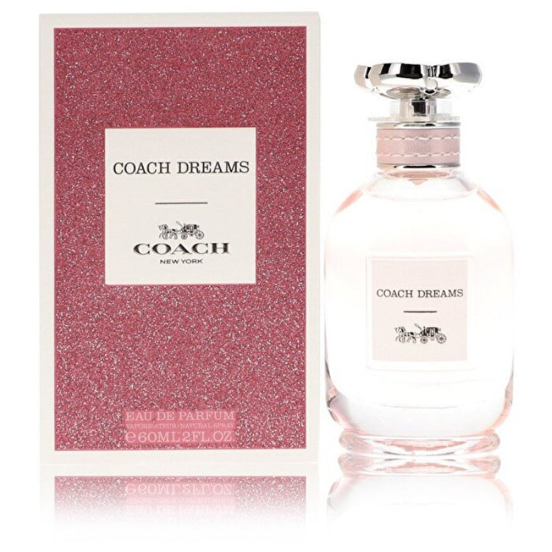 A bottle of Coach Dreams Eau de Parfum with a pink label and cap, next to its pink packaging box.