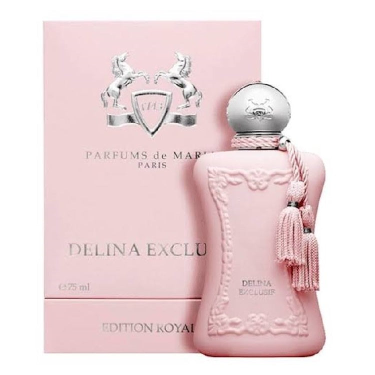 A pink bottle of Delina Exclusif perfume by Parfums De Marly with a decorative box behind it. The bottle has a decorative design, a tassel, and a silver cap.