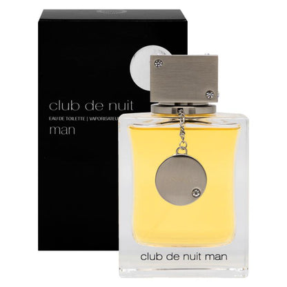 A bottle of Club de Nuit Man Eau de Toilette by Armaf, with a yellowish liquid visible through the clear glass and a silver cap attached to a chain. The product is presented with its black box packaging, featuring the product name and barcode.