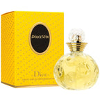 A photograph of a perfume bottle and box for Dolce Vita by Dior. The bottle is clear with a yellow liquid and has a gold cap.