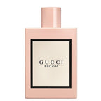 A pink bottle of Gucci Bloom Eau de Parfum with a white label displaying the name of the fragrance.