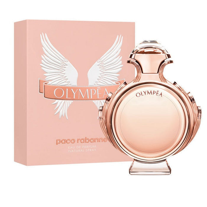 A product image featuring a perfume bottle and box for Olympea by Paco Rabanne. The bottle is rose gold colored with a decorative top and the box is pink with white angel wings graphics.