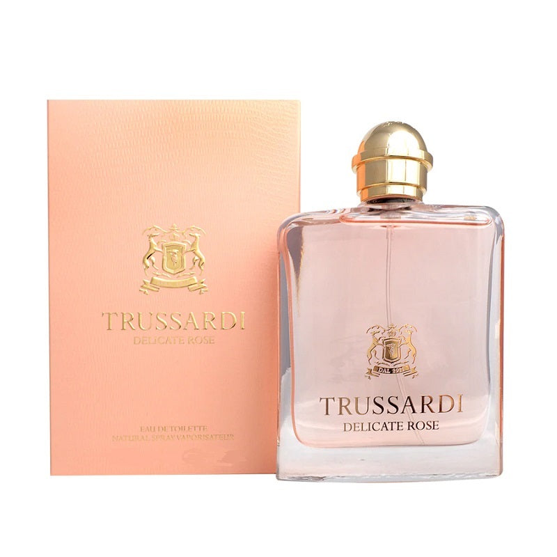 A bottle of Trussardi Delicate Rose eau de toilette next to its pink packaging box with gold accents.