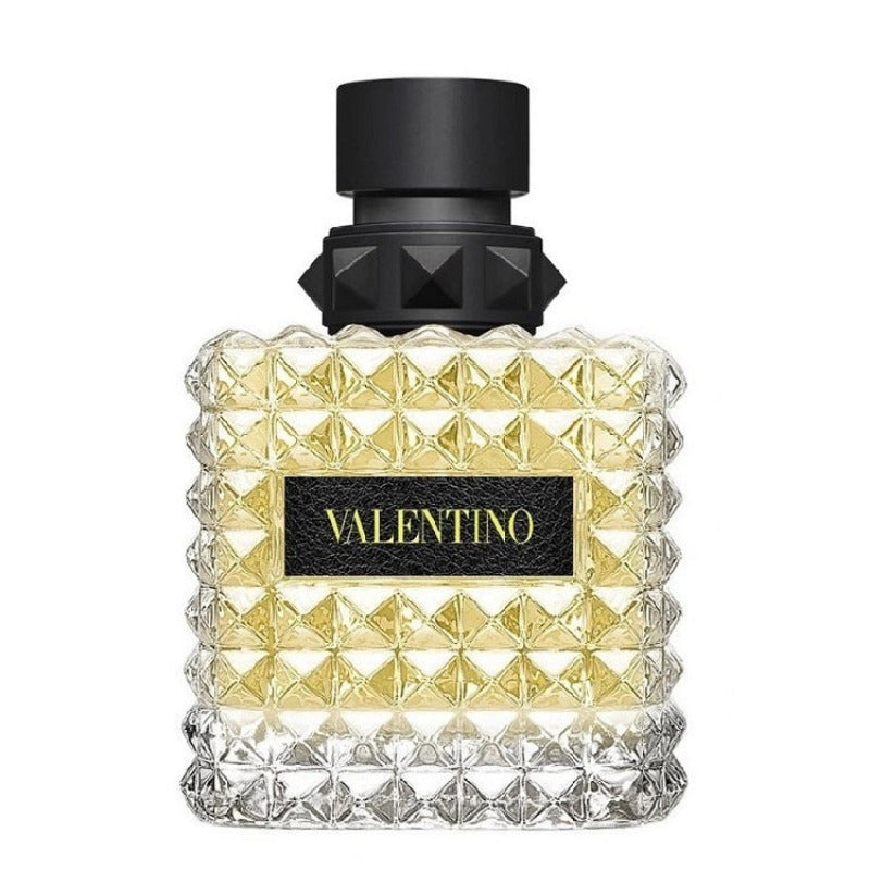 A glass bottle of Valentino Born In Roma Yellow Dream Eau de Parfum with a black cap and a label featuring the brand name in gold lettering on a yellow background.