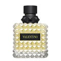A glass bottle of Valentino Born In Roma Yellow Dream Eau de Parfum with a black cap and a label featuring the brand name in gold lettering on a yellow background.
